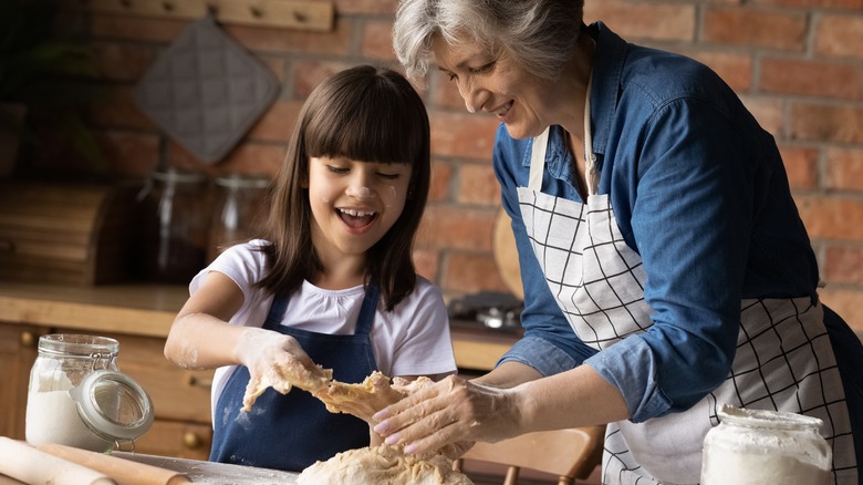 Girl and grandmother kneading dough