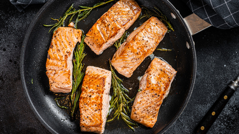 cooking fish in steaming skillet