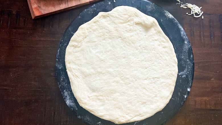 uncooked pizza crust on tray 