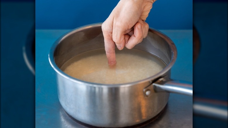 Finger in pot of rice and water