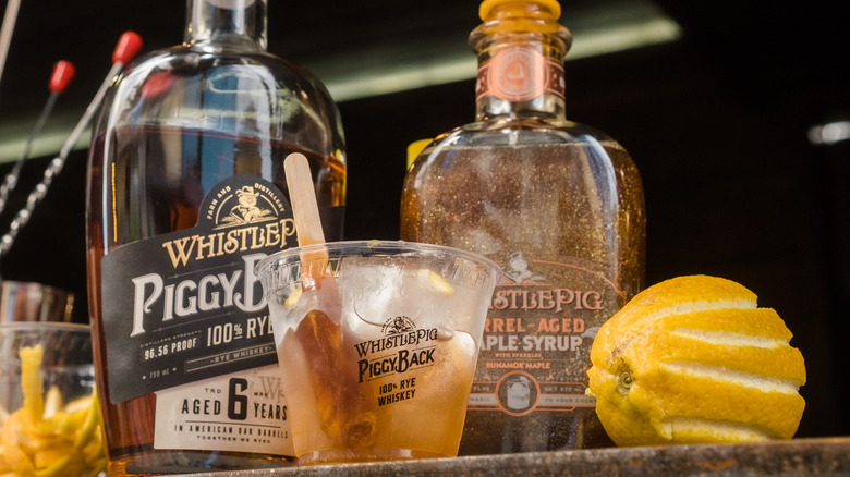 WhistlePig bottles and plastic cup with lemon