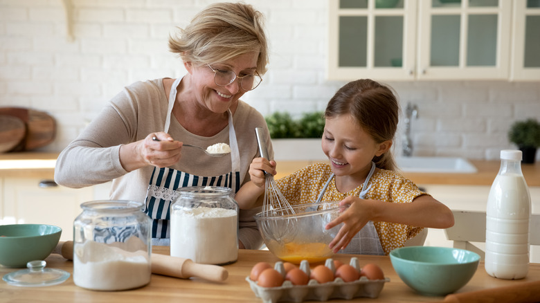 Older woman and girl mixing ingredients in a glass bowl