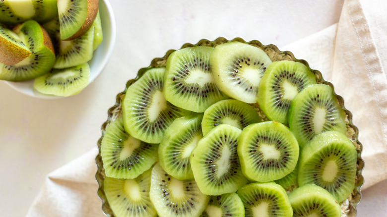 Kiwi tart next to cut kiwi