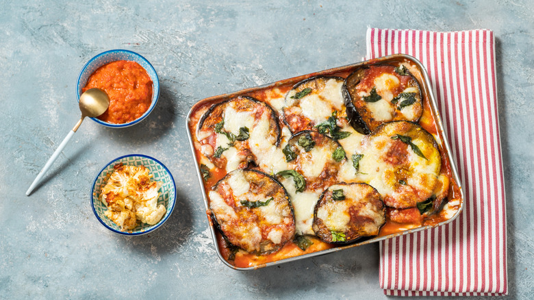 Eggplant parmesan in pan sitting on teal toul