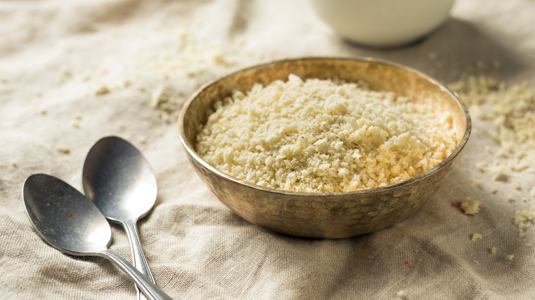 Breadcrumbs in bowl next to metal spoons