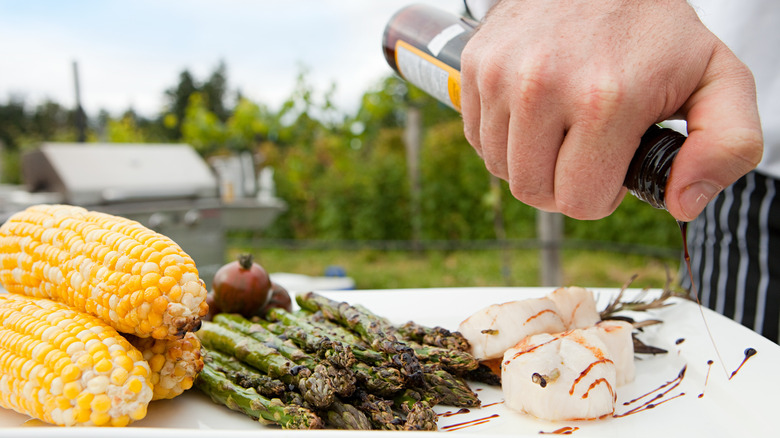 person drizzling balsamic vinegar over food