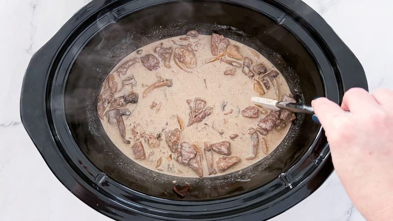 stirring stroganoff ingredients in crock 