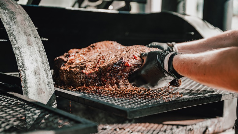 Hands putting meat in the smoker