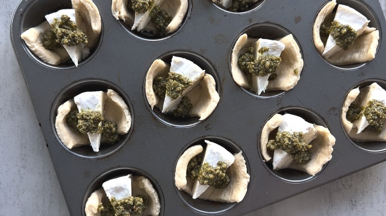 brie topped with pesto in muffin tin