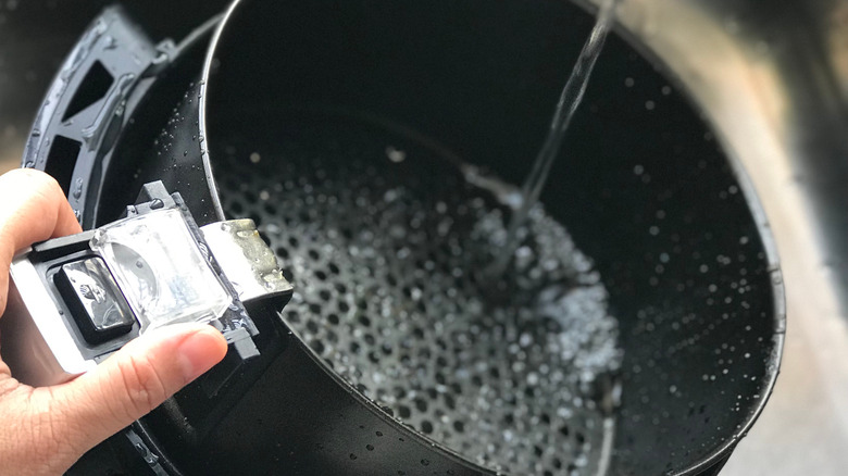 Rinsing air fryer basket in water