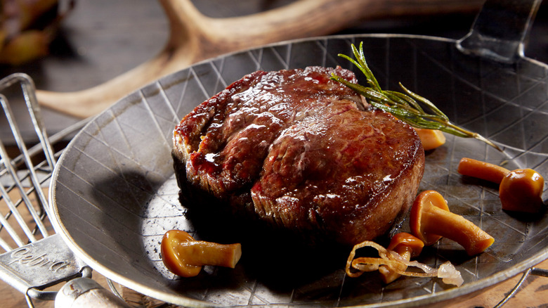 Cooked venison in frying pan with mushrooms