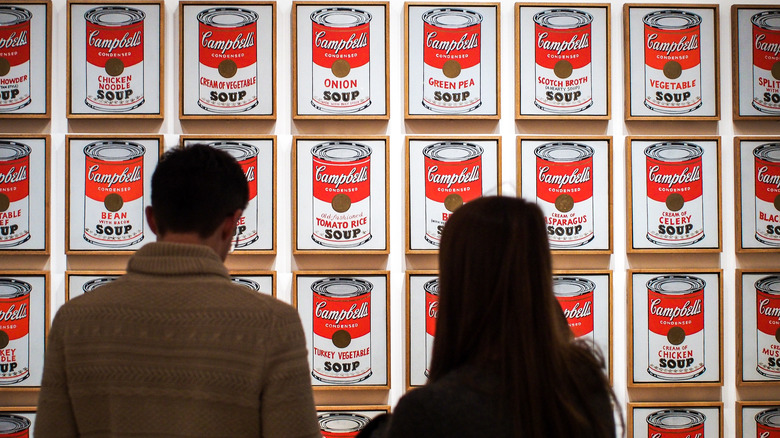 Two people look at Campbell soup paintings