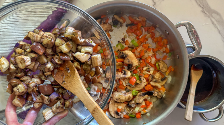 adding eggplant to pan