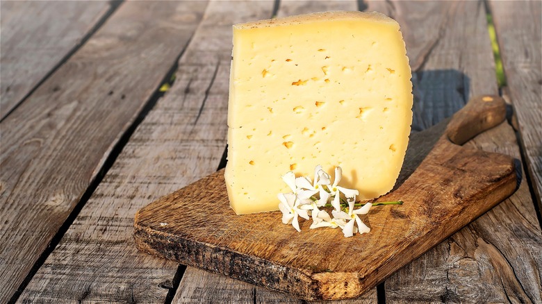 Wedge of Asiago cheese on board