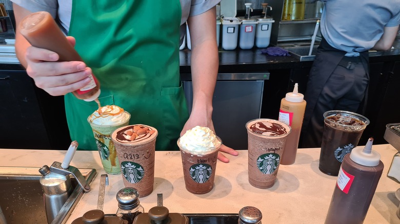 starbucks barista adding syrup to drinks