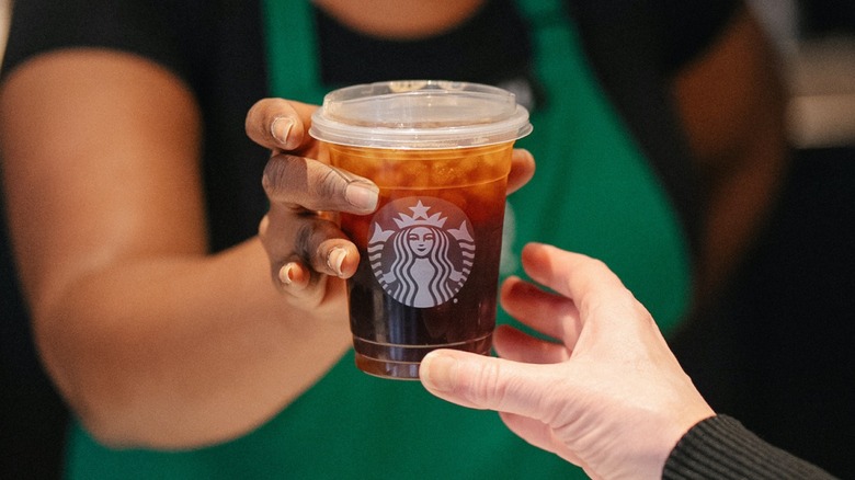 Starbucks barista handing an iced coffee to a customer