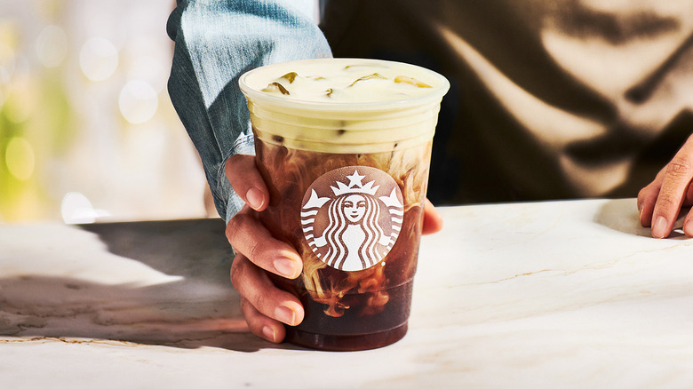 Starbucks employee holding an Oleato drink