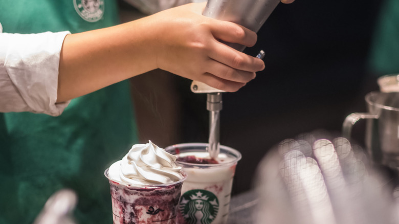 woman adding whipped cream to Starbucks drinks