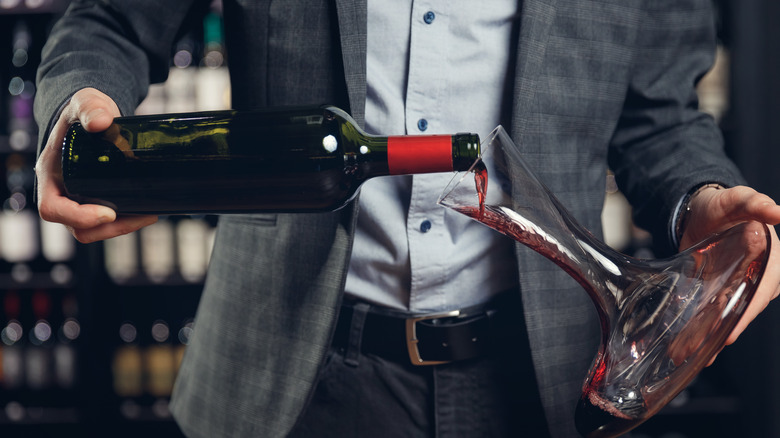 Person pouring wine into decanter.