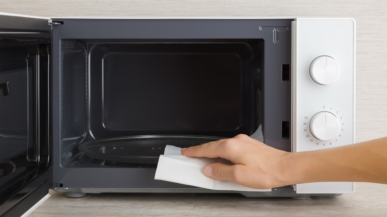 person wiping down microwave