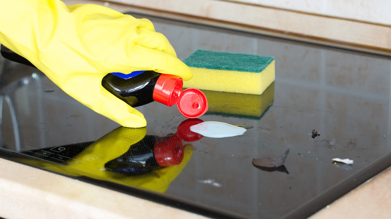 person cleaning glass stovetop