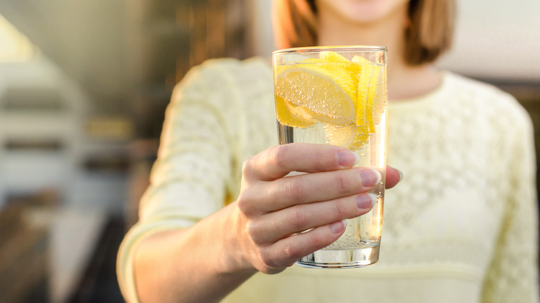 holding glass of lemon water