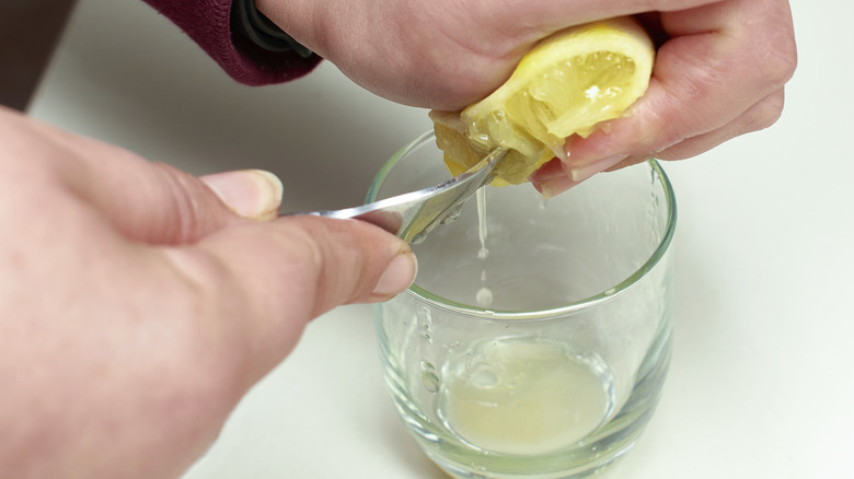juicing lemon into glass