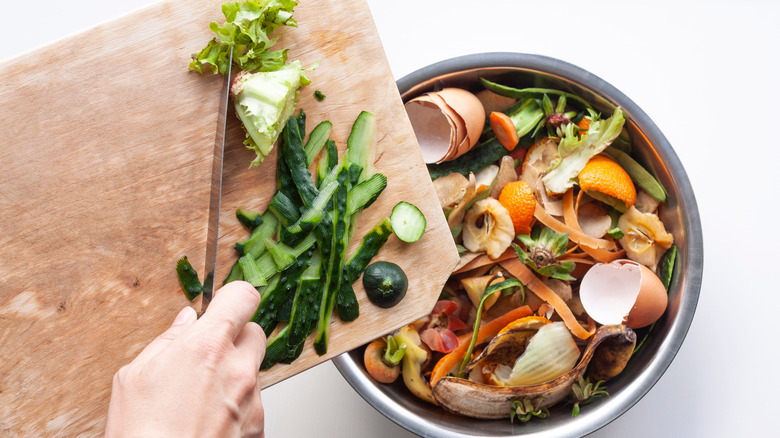 knife scraping food scraps off cutting board