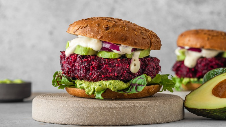 purple veggie burger with avocado sitting on pedestal 