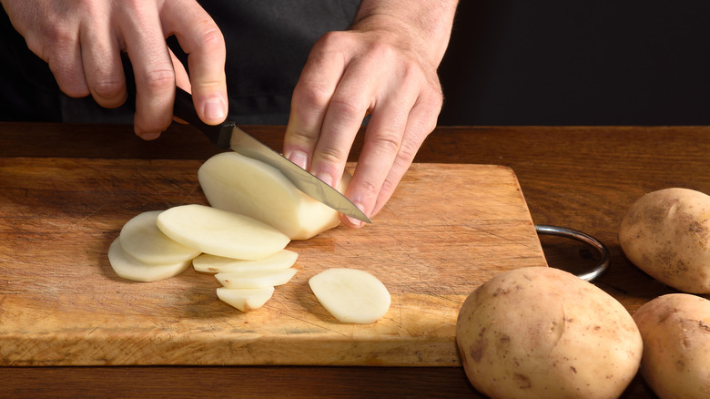 slicing potatoes on a cutting board