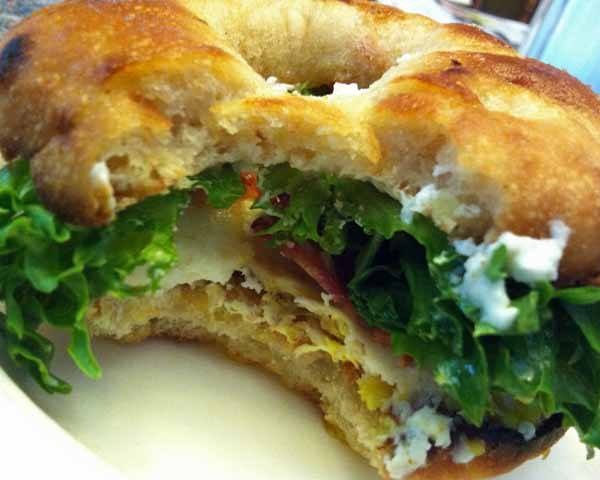 Sunnied Egg Bialy Sandwich with Bacon, Arugula, Goat Cheese, and Balsamic Glaze