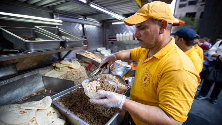 Halal Guys employee putting together food cart order