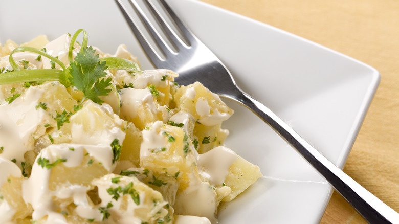 White plate of potato salad with fork