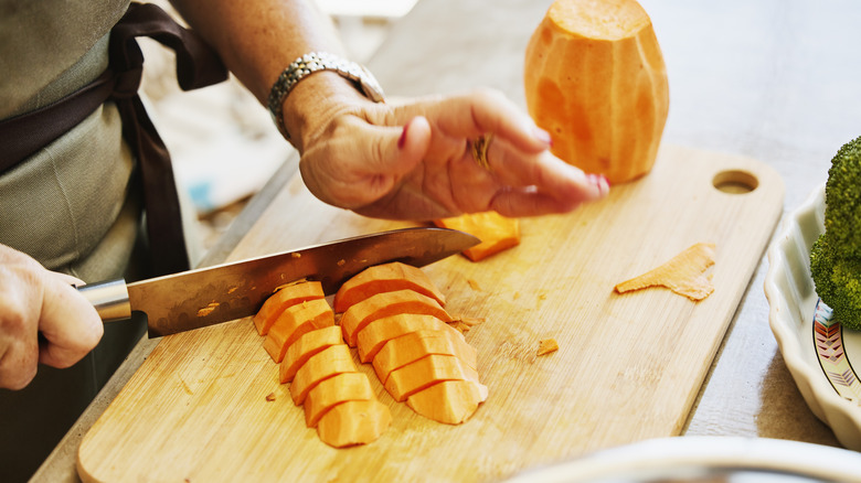 Chopping up peeled sweet potatoes