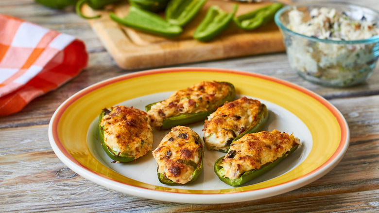 Jalapeno poppers on a plate with jalapenos on a cutting board