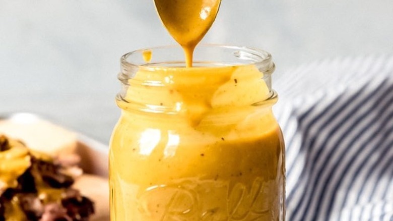 mustard bbq sauce in jar with dripping spoon