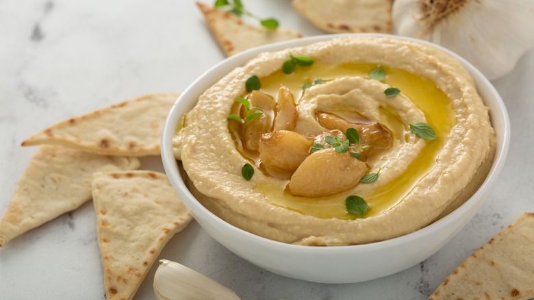 bowl of hummus with garlic cloves on top