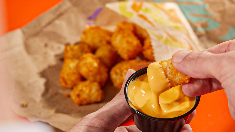 Taco Bell Breakfast Tots being dipped into cheese sauce