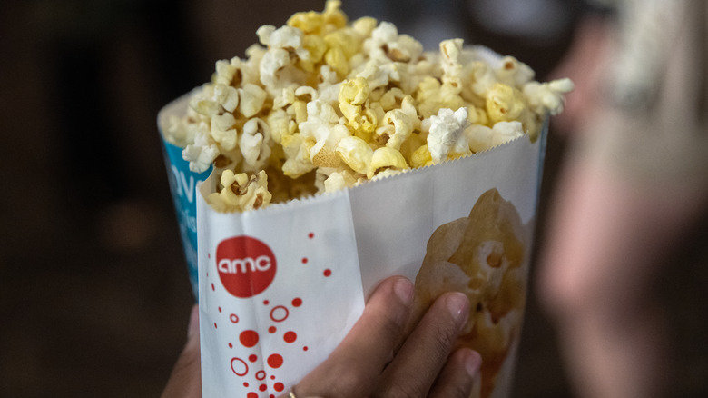 Person holding bag of AMC popcorn