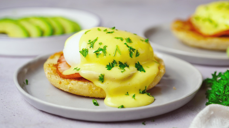 Eggs benedict with avocado in the background