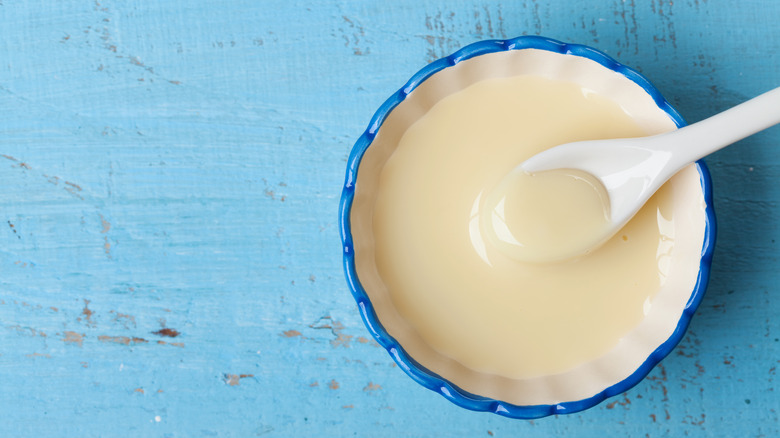 Bowl of sweetened condensed milk on blue wood