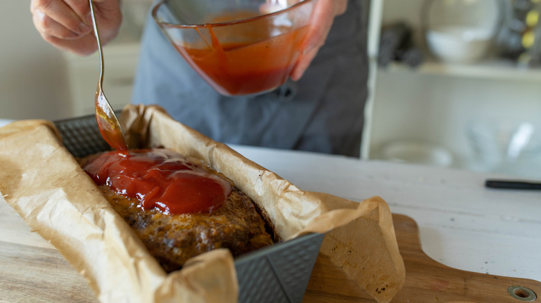 Person glazing meatloaf.