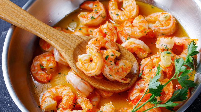 Shrimp scampi in a pan with wooden spoon