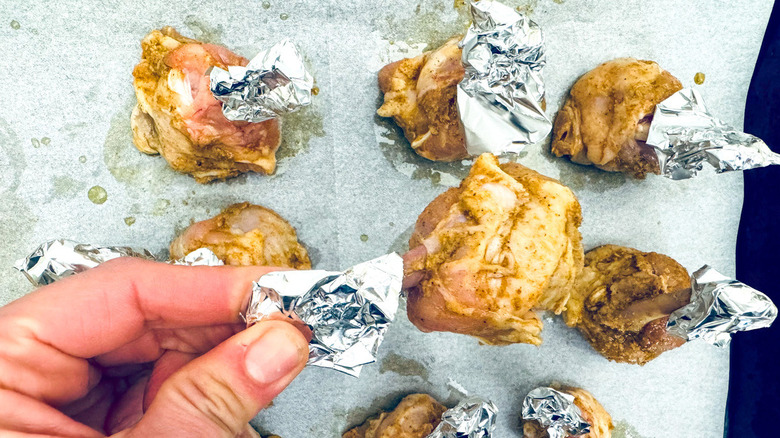 hand holding foil-wrapped chicken