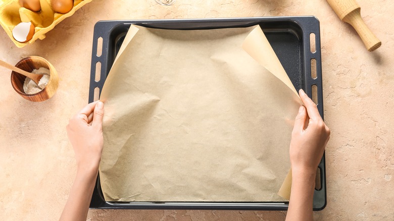 person putting parchment paper in pan