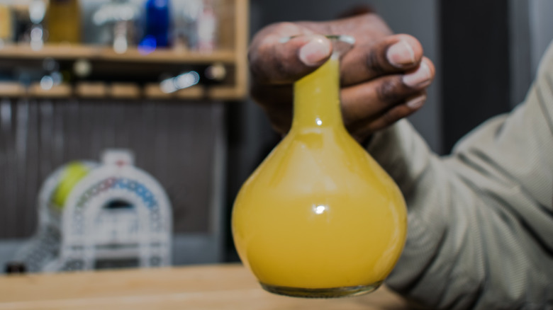 Person holding tej beaker 