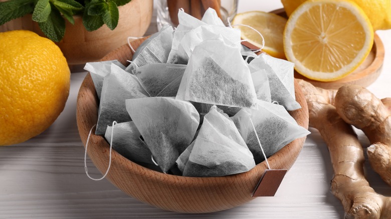 tea bags in a bowl surrounded by lemons and ginger