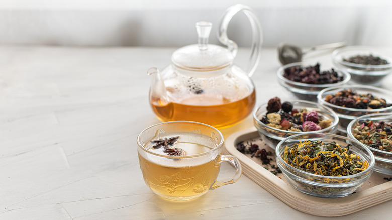 various tea leaves and tea pot and cup with floral tea