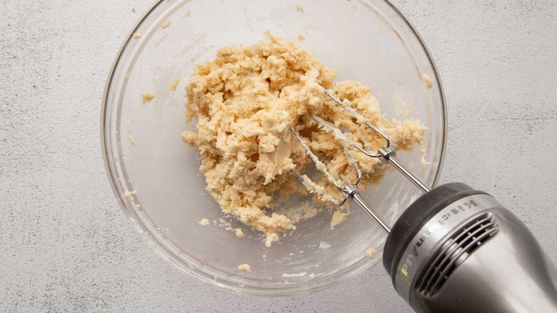 Dough in a clear bowl with a handheld mixer