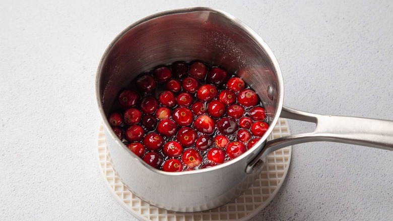 Cranberries in clear liquid in a metal pot